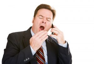 Man Yawning at Work While on the Phone